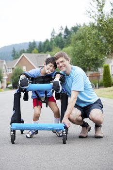 Father kneeling next to disabled son standing in walker