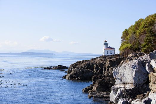 Blue waters of coast of San Juan island, Washington state. Lighthouse at Whale Watch Park in background
