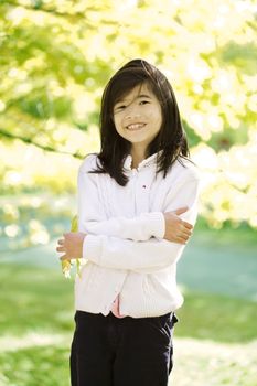 Little biracial asian girl standing amongst bright autumn leaves