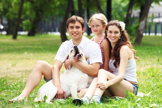 Young Family Outdoors in summer park with a dog