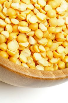 Yellow Split Peas in Wood Bowl closeup on white background