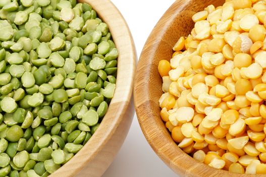 Green and Yellow Split Peas in Wooden Bowls closeup on white background