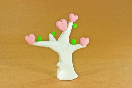Tree of love made from plasticine pink heart white trunk green leaves on brown paper background