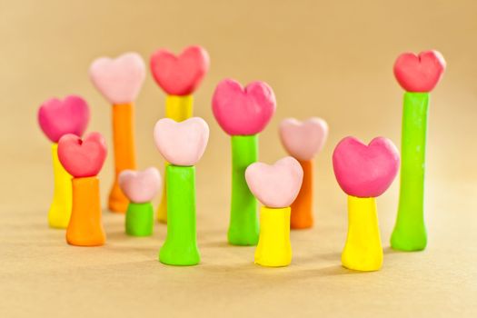 group of sweet color heart on post made from plasticine on brown paper background