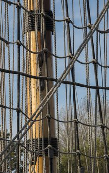 the wooden mast of a ship with the rig and ropes