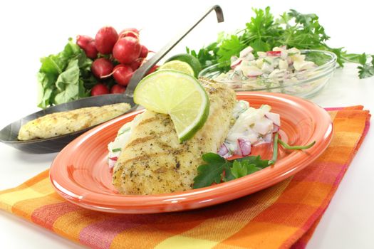 hake with lime on potato salad and parsley on a light background