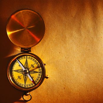 Antique brass compass over old paper background