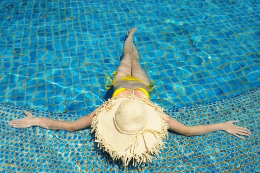 Girl with hat at tropical swimming pool