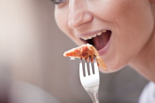 young woman is eating a pizza in restaurant outdoor