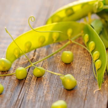 Fresh green peas pods on a wooden table