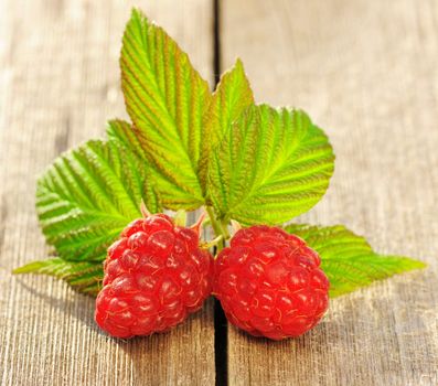 Raspberry with leafs on wooden table