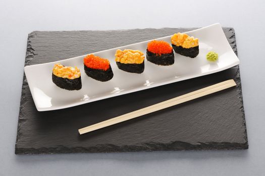 Tobiko and spice sushi on a slate plate