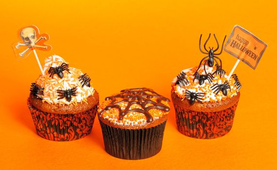 Halloween cupcakes with decoration over orange background