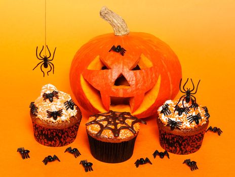 Halloween cupcakes with decoration over orange background