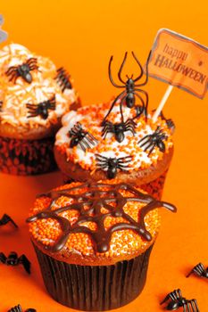 Halloween cupcakes with decoration over orange background