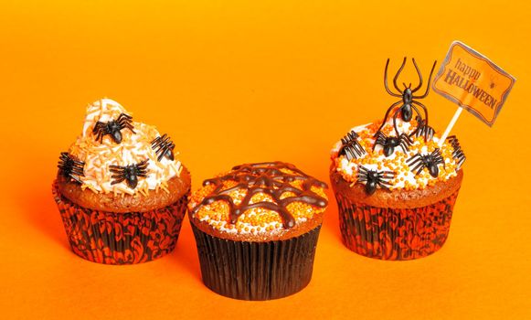 Halloween cupcakes with decoration over orange background