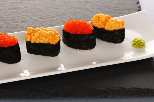 Tobiko and spice sushi on a slate plate