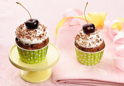 Cupcakes with whipped cream and cherry on a cloth