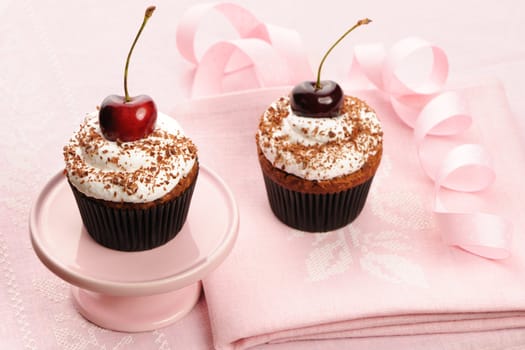 Cupcakes with whipped cream and cherry on a cloth