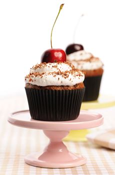 Cupcakes with whipped cream and cherry on a table