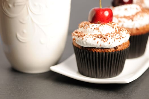 Cupcakes with whipped cream and cherry on a table