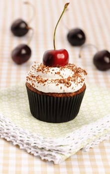 Cupcakes with whipped cream and cherry on a table