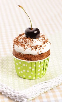 Cupcakes with whipped cream and cherry on a table