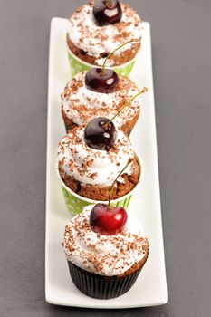 Cupcakes with whipped cream and cherry on a table