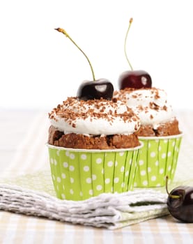 Cupcakes with whipped cream and cherry on a table