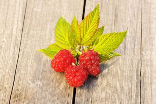 Raspberry with leafs on wooden table