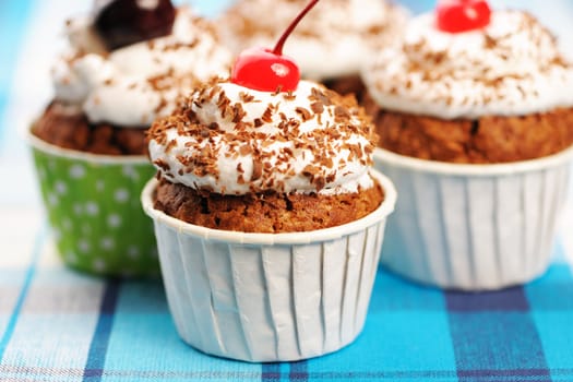 Cupcakes with whipped cream and cherry on a cloth