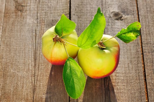Fresh apples with leaves on wooden table