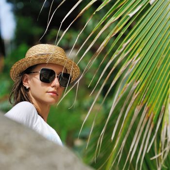 Woman in sunglasses near palm tree wearing hat
