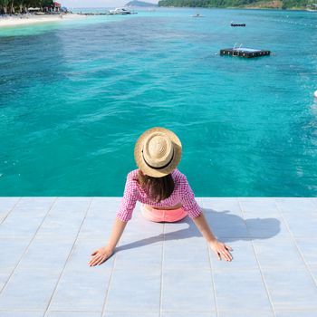 Woman at beach jetty wearing hat