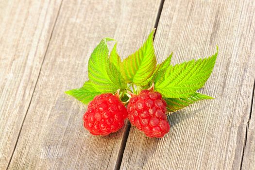 Raspberry with leafs on wooden table