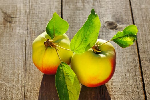 Fresh apples with leaves on wooden table