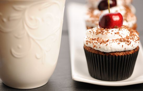 Cupcakes with whipped cream and cherry on a table