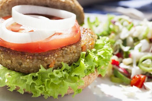 Tempting quinoa veggie burger with tomato and onion slices.