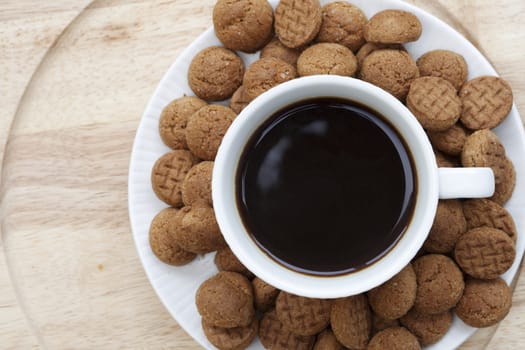 Kruidnootjes surrounding a cup of coffee seen from directly above.
