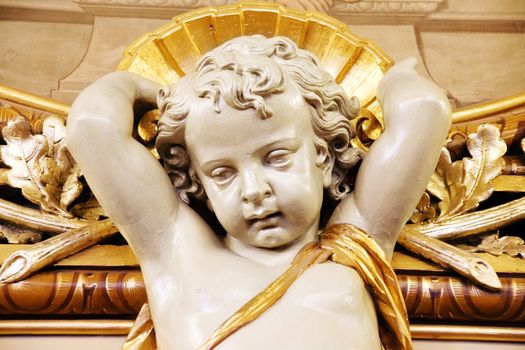 Beautiful plaster cherub detail with gold leaf scallop and oak leaves, all part of architectural decorations in an french historical building, Lyon, France.