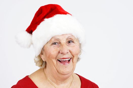 Grand-mother or elderly woman with big happy smile wearing Santa Claus hat; perfect for Christmas and seniors themes