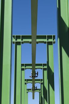 Detail of a small gantry crane painted green against the blue sky