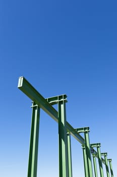 Detail of a small gantry crane painted green against the blue sky