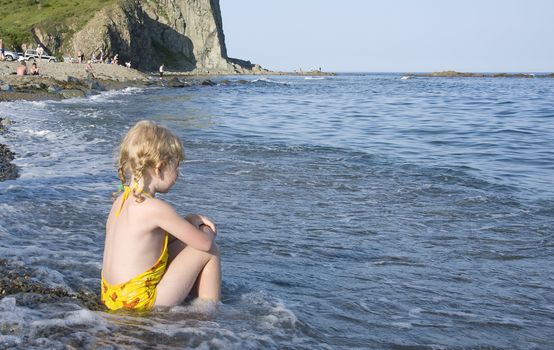 little girl sitting on the bank of  Japan Sea 