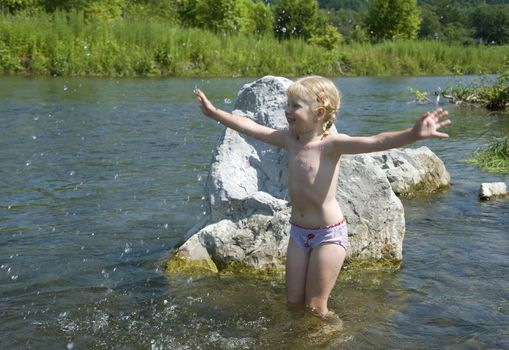 little girl playing on the river bank