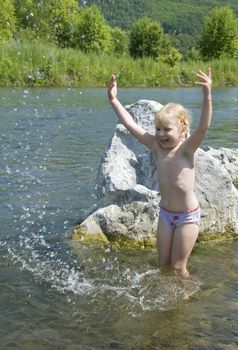 little girl playing on the river bank