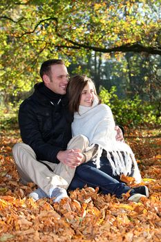 Loving young couple sitting in a close embrace sharing an intimate moment together as they enjoy the solitude of an autumn forest Loving young couple sitting in a close embrace sharing an intimate moment togethe as they enjoy the solitude of an autumn forestr