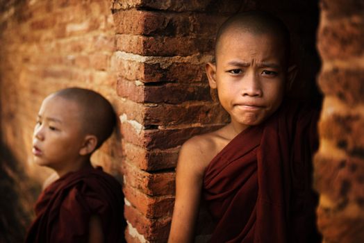 Two young buddhist novice monk outside a temple background.