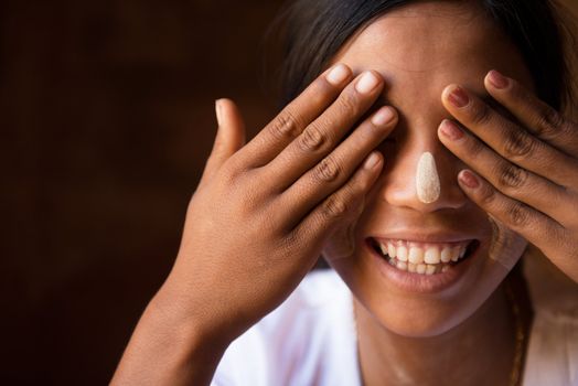 Shy Myanmar girl covering her eyes with hands