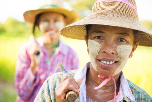 Portrait of a two Myanmar farmer with thanaka powdered face who works in the field